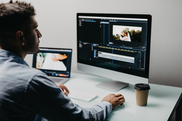 back view of video editor using computer working with fotoage at his office