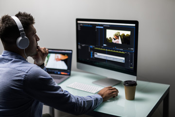 back view of video editor using computer working with fotoage at his office