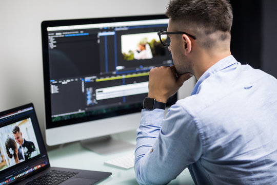 Young male editor editing video on computer at workplace office