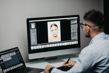Professional photographer works in photo editing app software on his personal computer. Photo editor retouching photos of beautiful girl.