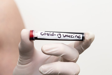 Covid-19 vaccine in blood tube, doctor wearing medical gloves holding a blood tube with positive Coronavirus 2019-nCoV Blood Sample with injection.