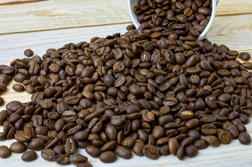 scattered coffee beans from paper cup on wooden table