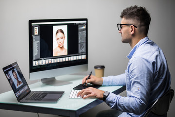 Professional photographer works in photo editing app software on his personal computer. Photo editor retouching photos of beautiful girl.