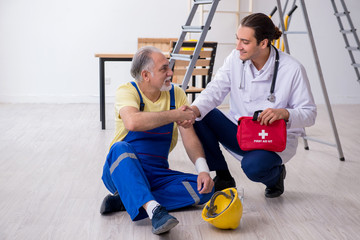 Young male doctor and old contractor in first aid concept