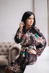 Beautiful brunette woman demonstrating spring clothes in studio. Model stand near the window