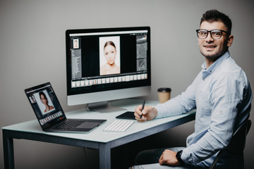 Professional photographer works in photo editing app software on his personal computer. Photo editor retouching photos of beautiful girl.