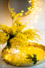 Bouquet of yellow mimosa flowers with bright gold interior decor with light spots