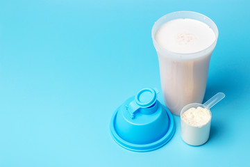 With a protein shake and a measuring spoon on blue background, copy space.