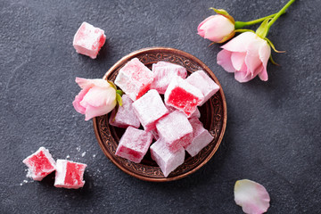 Turkish delights lokum, rose flavour in a copper plate. Dark background. Top view.