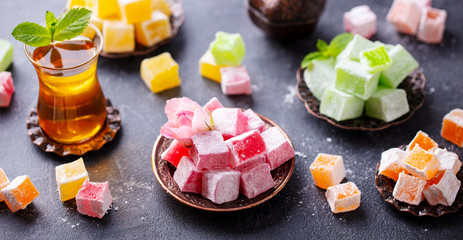 Assortment of Turkish delights with glass of tea. Grey background. - 330355265