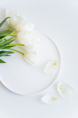 Fototapeta na wymiar Bouquet of white tulips on round ceramic plate