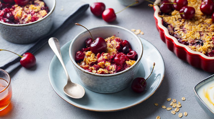 Healthy breakfast. Cherry, red berry crumble in bowl. Grey background. Close up.