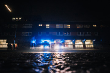 Fire station at night with fire trucks responding to emergency call and leaving