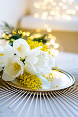 Bouquet of white tulips and mimosa flowers on mirror tray