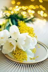 Bouquet of white tulips and mimosa flowers on mirror tray