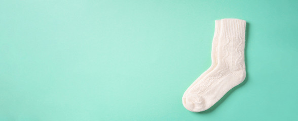 Pair of white woolen knitted socks on blue background. Top view. Copy space. Christmas and New Year cozy holiday composition. Winter weather. Banner