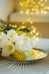 Bouquet of white tulips and mimosa flowers on mirror tray