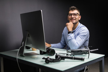 Young man sitting at table with different devices and gadgets at office