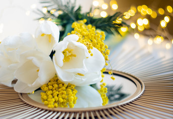 Obraz na płótnie Canvas Bouquet of white tulips and mimosa flowers on mirror tray