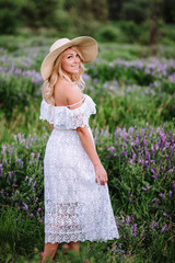 girl in a hat in a summer white dress. blonde in the field