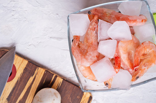 frozen shrimps  in bowl with vegetables on white table. flat lay