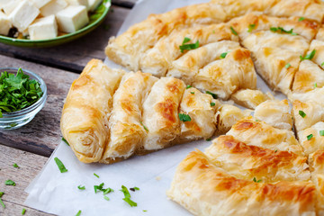 Traditional feta cheese phyllo pastry pie, banitsa. Wooden background. Close up.