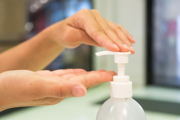 Female using alcohol gel as hand sanitizer at shopping center for prevent the spread of germs and bacteria and avoid infections corona virus. Hygiene concept