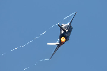 F-35 Lightning II in a tight turn, with afterburner on and condensation trails at the wing’s tips