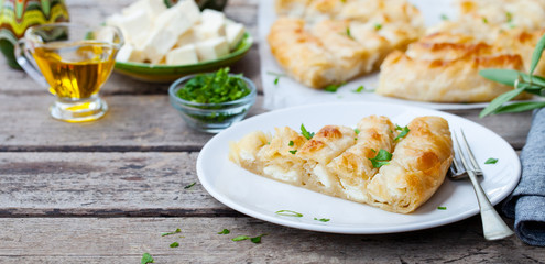 Traditional feta cheese phyllo pastry pie, banitsa. Wooden background. Copy space.
