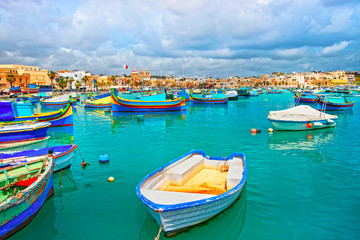 Fototapeta na wymiar Luzzu boats in Marsaxlokk harbor of bay Mediterranean sea Malta