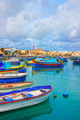 Fototapeta na wymiar Luzzu boats on Marsaxlokk Port embankment in bay Mediterranean sea