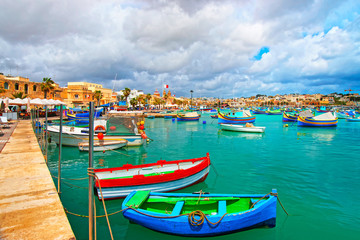 Fototapeta na wymiar Luzzu boats at Marsaxlokk Port in Mediterranean sea Malta