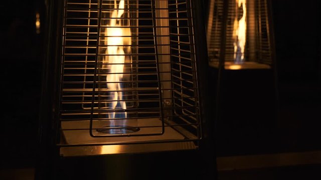 Gas heaters stand on the veranda, open cozy fire. Warmth and comfort. Flame of street gas heaters 4k