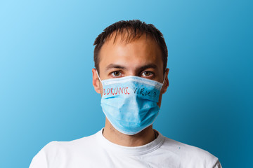 Portrait of a sick man wearing medical mask with coronavirus text at blue background. Coronavirus concept. Protect your health.