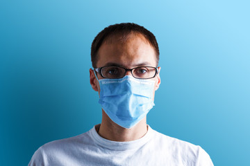 Portrait of a sick man wearing medical mask with coronavirus text at blue background. Coronavirus concept. Protect your health.