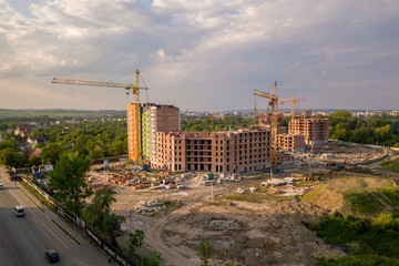 Aerial view of building site. Apartment or office building under construction. Tower cranes on suburb landscape and blue sky copy space background.