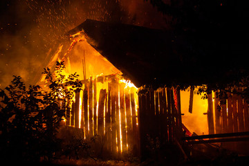 Wooden house or barn burning on fire at night.