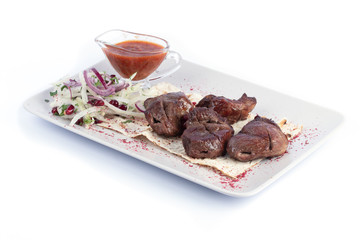 Lamb shish kebab with fresh vegetables and red sauce on a white plate for menu and web