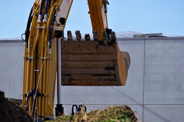 Bagger in Aktion, mit Himmel und Gebäude im Hintergrund