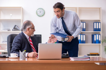 Old boss and young male employee in the office