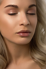 Fototapeta premium Closeup portrait of a woman with developing straight hair. Sweet tender young girl blonde. Natural lipstick, transparent clean skin. Skin care natural cosmetics in the spa salon or cosmetology.