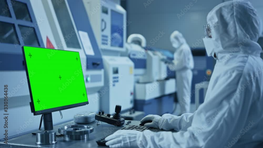 Fototapete factory cleanroom: engineer wearing coveralls does system control on computer, uses controller, gree