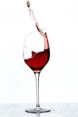 Close up view of splashing red wine in glass isolated on white background. 