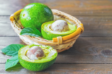 ripe avocados in a basket and on the table close-up. background with avocado. avocado halves and green leaves close-up.