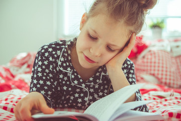 Adorable little girl reading book having quarantine because of coronavirus