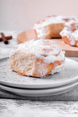 Cinnamon roll topped with cream cheese glazing on the white wooden table