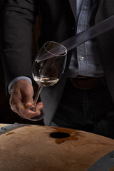 Sommelier makes a selection of red wine from an oak barrel. ecological wine production on the farm.
