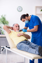 Injured old man visiting young male doctor traumatologist