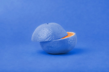 The concept of non-standard thinking and creativity. On a blue background, a blue tangerine is cut in half. The inside of a Mandarin orange.