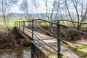 Fototapeta premium Little iron bridge across the little river and a green meadow